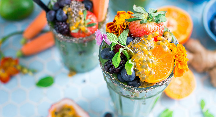 Colorful fruit smoothies with fresh garnishes.