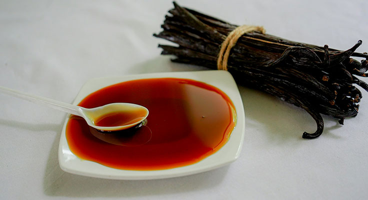 Vanilla extract in spoon and vanilla pods.