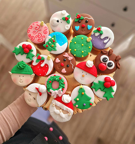 Hand holding festive decorated Christmas cookies bouquet.