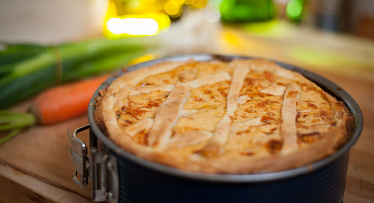 Freshly baked savory pie on wooden counter.