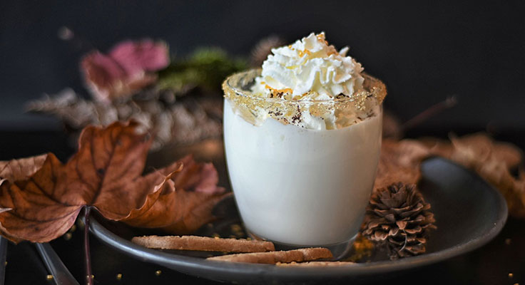 Festive eggnog with whipped cream and autumn leaves