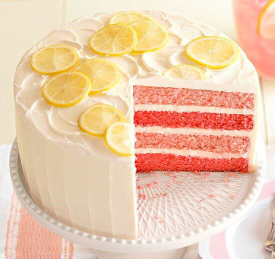 Lemon-topped pink layered cake on white stand.