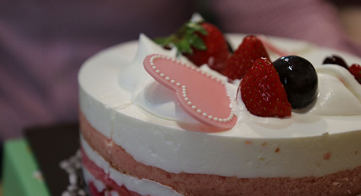 Fresh strawberry cream cake with decorative topper.