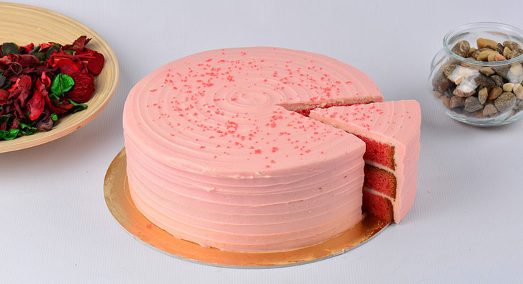 Pink frosted cake with one slice removed.