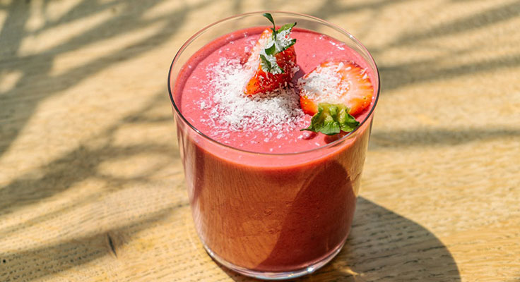 Strawberry smoothie topped with coconut shavings.
