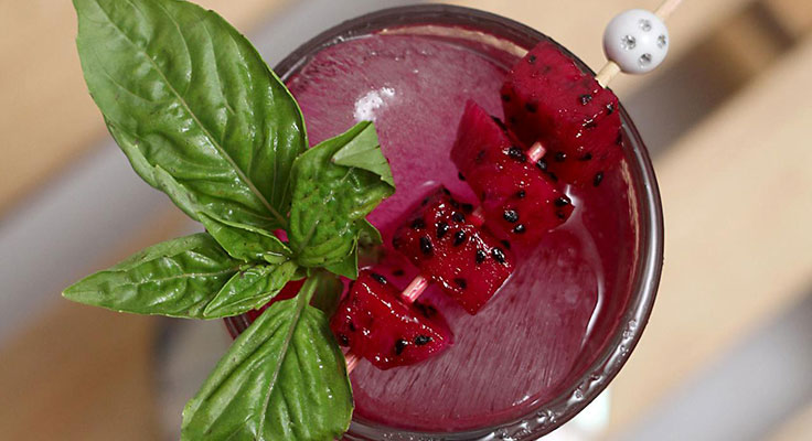 Fresh dragon fruit smoothie garnished with basil leaf.