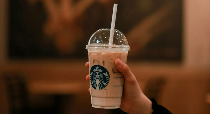 Hand holding Starbucks iced coffee in cafe.