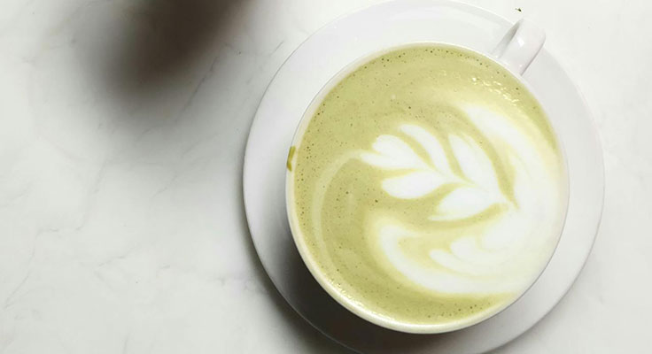 Matcha latte with art on marble surface.