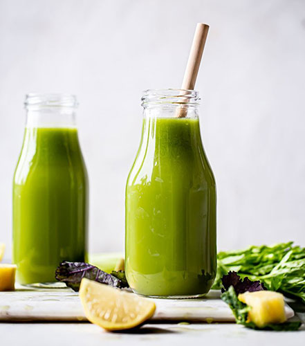 Fresh green juice in glass bottles with bamboo straws.