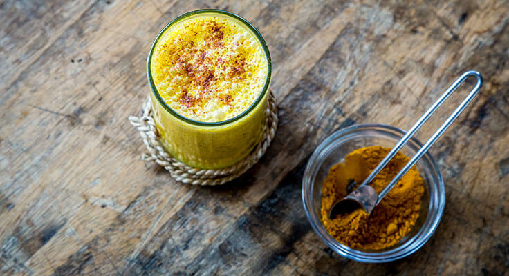 Golden milk turmeric latte on wooden table.