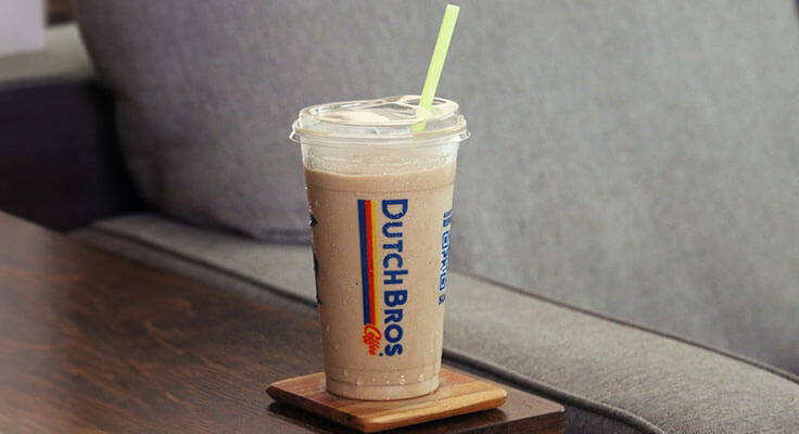 Iced coffee in a Dutch Bros cup on table.