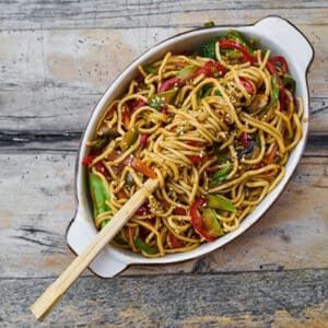 Vegetable stir-fry noodles in bowl with chopsticks.