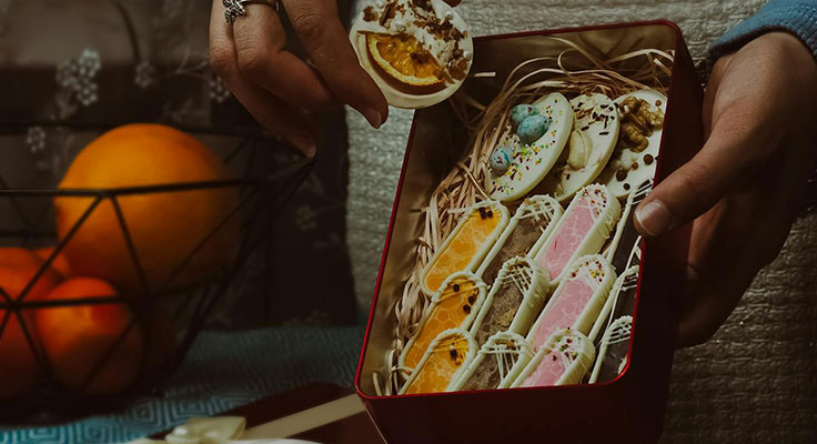 Person holding box of decorated cookies.