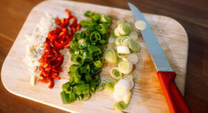 Chopped onions and peppers on cutting board with knife.