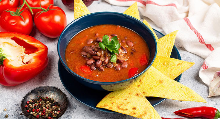 Hearty bean soup with fresh vegetables and tortilla chips.