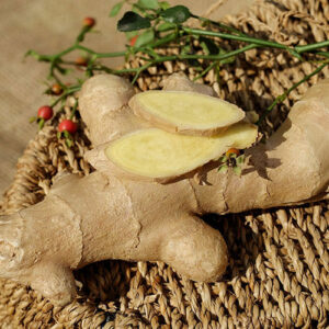 Fresh ginger root sliced on woven straw surface.