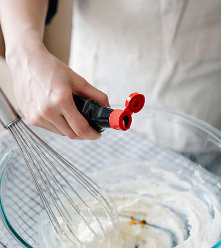 Pouring vanilla extract into whipped cream mixture.