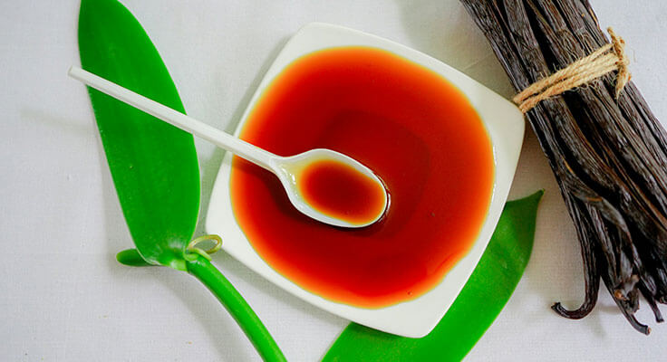 Vanilla pods and spoonful of vanilla extract.