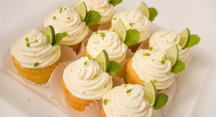 Lime cupcakes with creamy frosting and mint leaves.