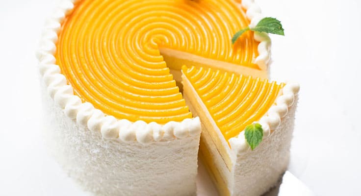 Sliced mango cheesecake with mint garnish.