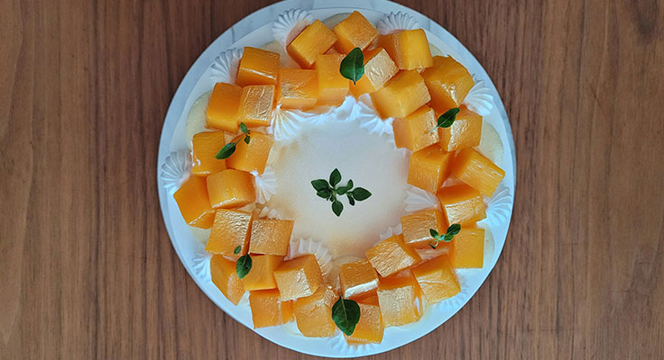 Fresh cut cantaloupe cubes on plate with basil garnish.