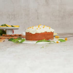 Carrot cake with cream cheese frosting on kitchen counter.