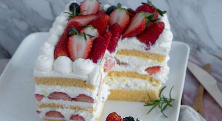 Fresh strawberry cream cake on white plate.