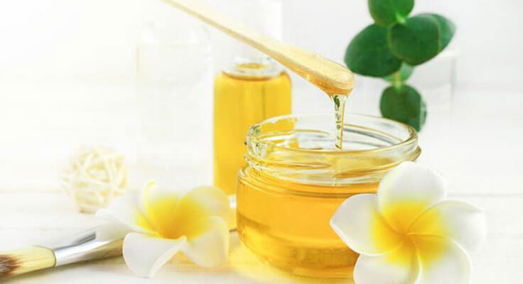 Natural honey jar and flowers on table.