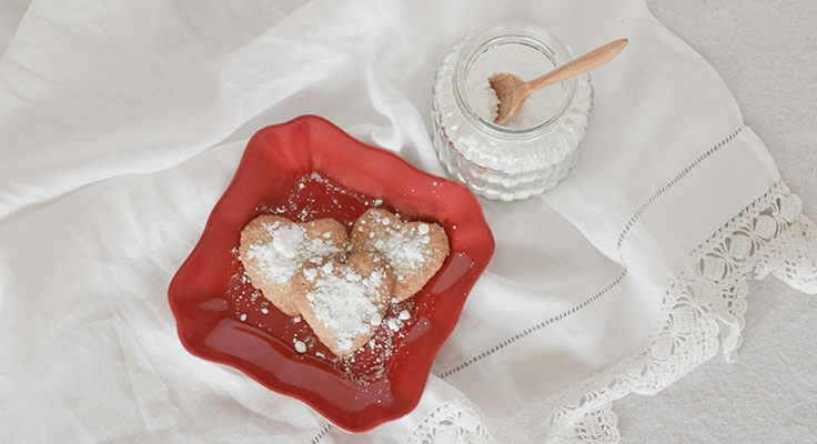 Heart-shaped cookies with powdered sugar, jar of honey.