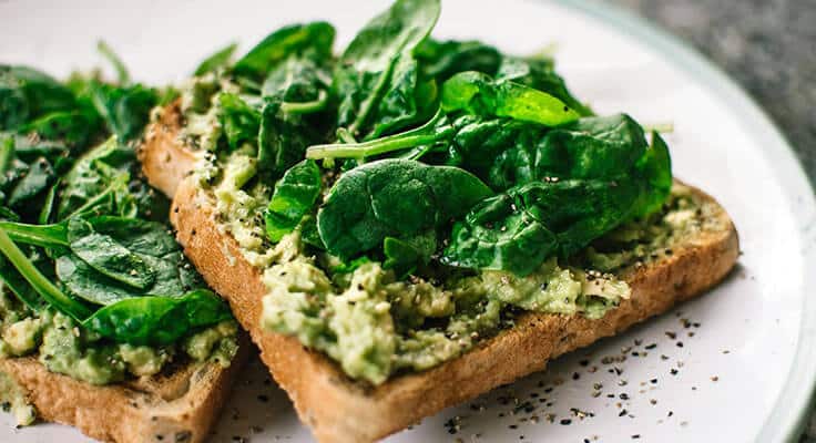 Spinach avocado toast on white plate