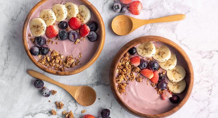 Two acai bowls with fruits and granola.