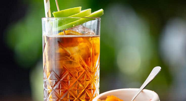 Iced tea with apple slices in glass.