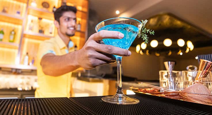 Bartender serving blue cocktail at modern bar.