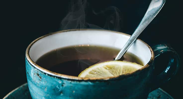 Steaming tea with lemon in blue cup.