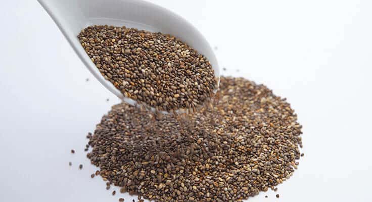 Chia seeds pouring from white scoop.