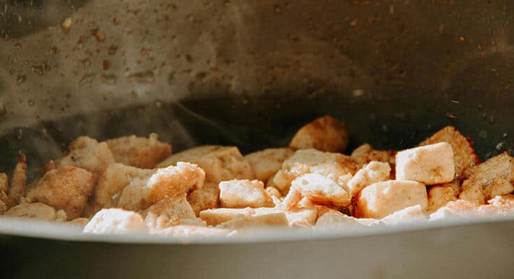 Sautéing chicken pieces in a pan.