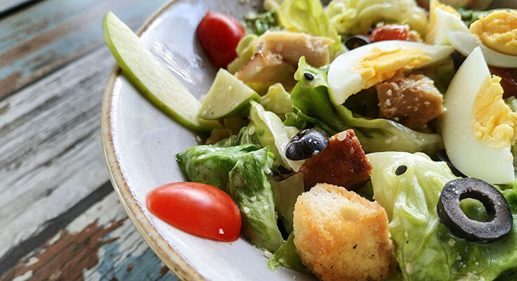Fresh Caesar salad on rustic table.
