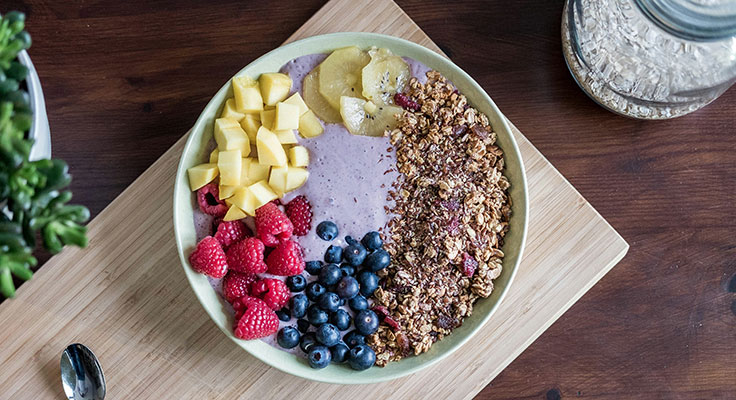 Colorful fruit smoothie bowl with granola topping.