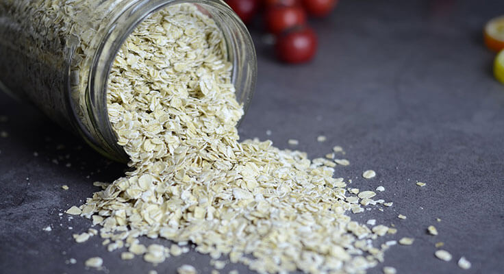 Spilled oats from jar on kitchen counter.