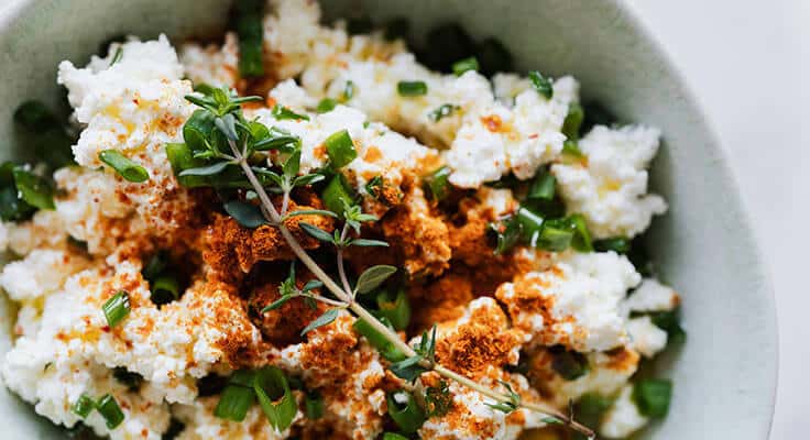 Seasoned cottage cheese with herbs in bowl.