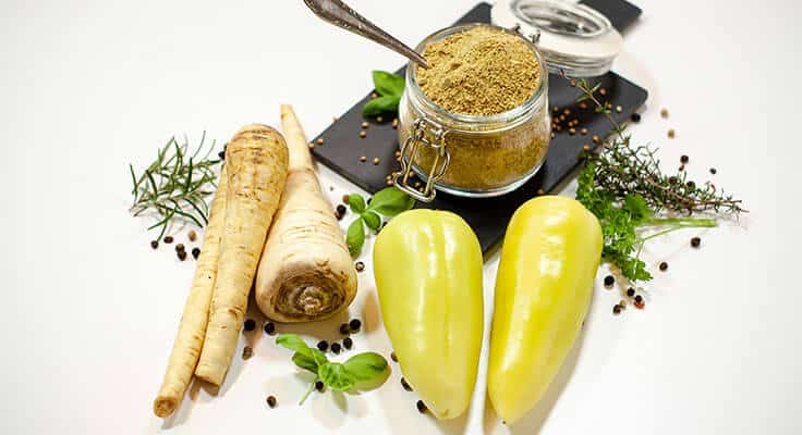 Fresh herbs, spices, and vegetables on white background.