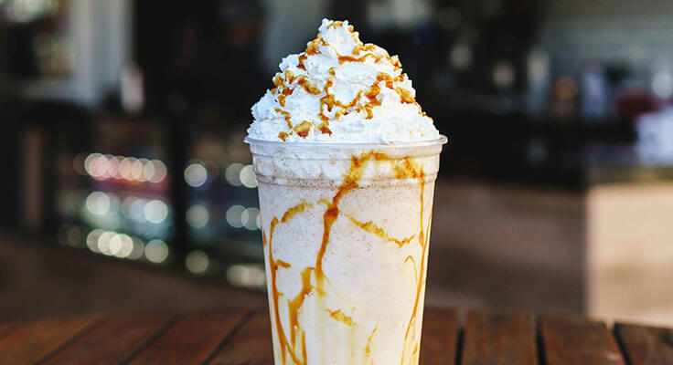 Caramel frappe with whipped cream on table.