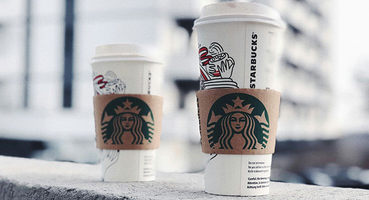 Two Starbucks coffee cups on urban background.