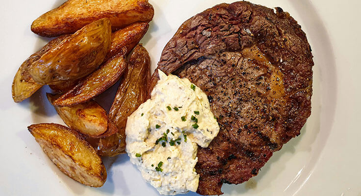 Grilled steak with roasted potatoes and herb butter.