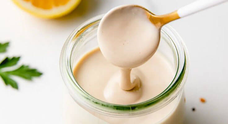 Creamy homemade mayonnaise in jar with spoon.