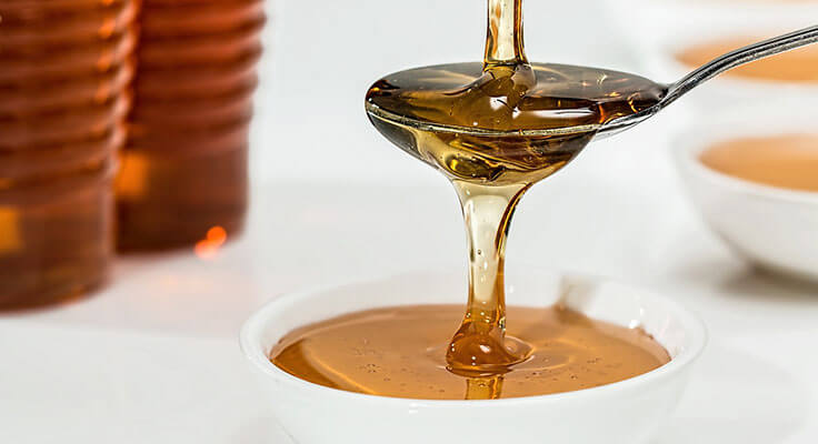 Honey pouring from spoon into bowl.