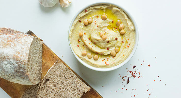 Homemade hummus with olive oil, bread, and spices.