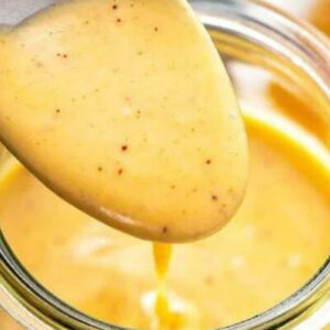 Spoonful of honey mustard dressing over jar.