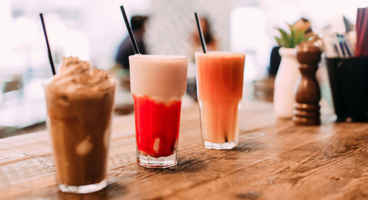 Three mixed drinks on a wooden table
