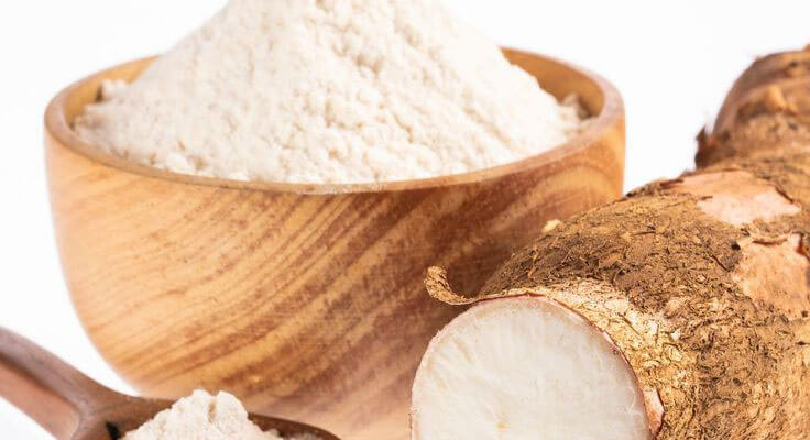 Cassava root and flour in wooden bowl